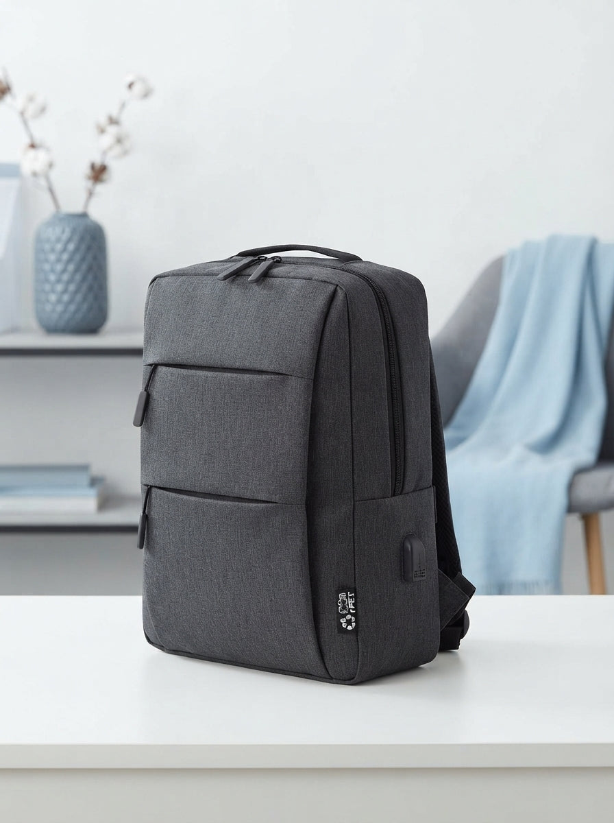 A sleek black 17-inch laptop backpack sitting on a clean, modern surface in a bright, professional office space.